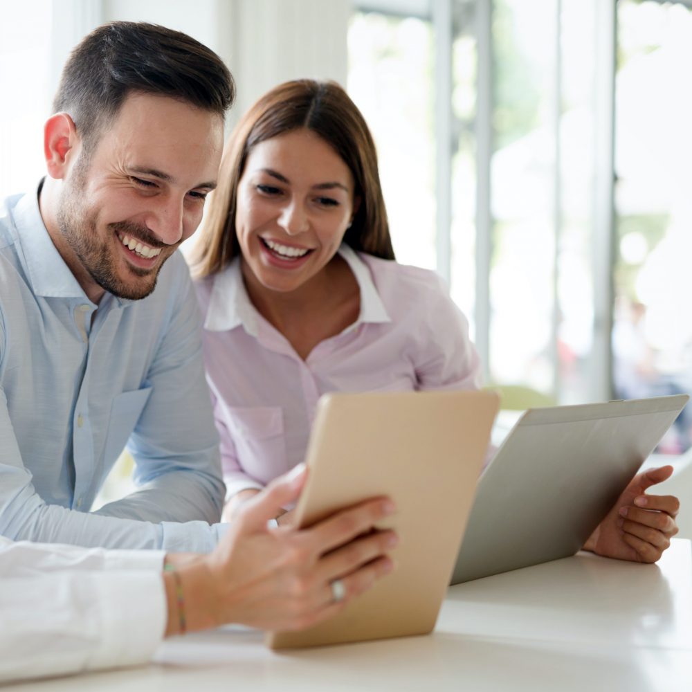 Happy business colleagues in modern office using tablet